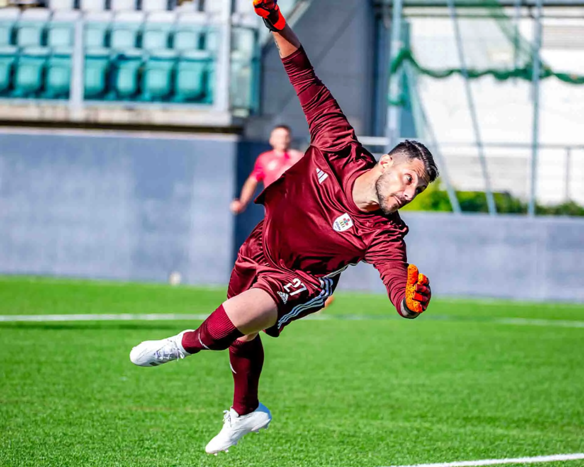 Football goalkeeper diving to save a ball that is going towards the goal